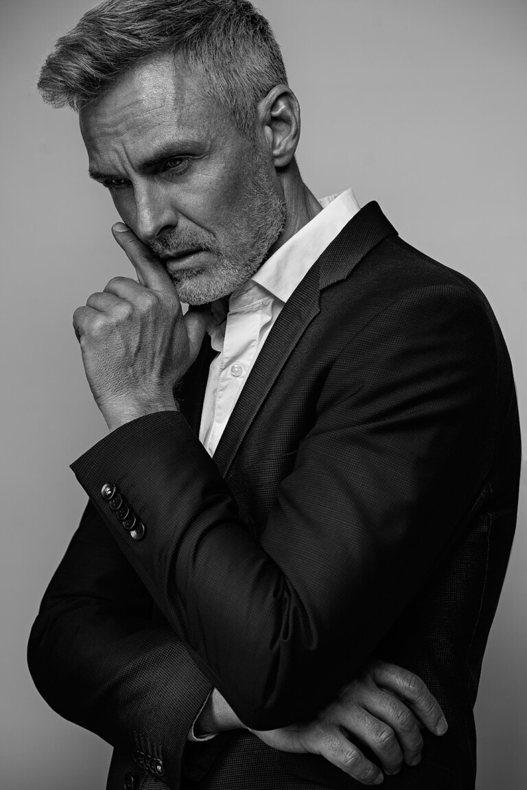 Schwarzweiß Business Portrait eines Mannes mit grauem Bart, Hand nachdenklich am Kinn