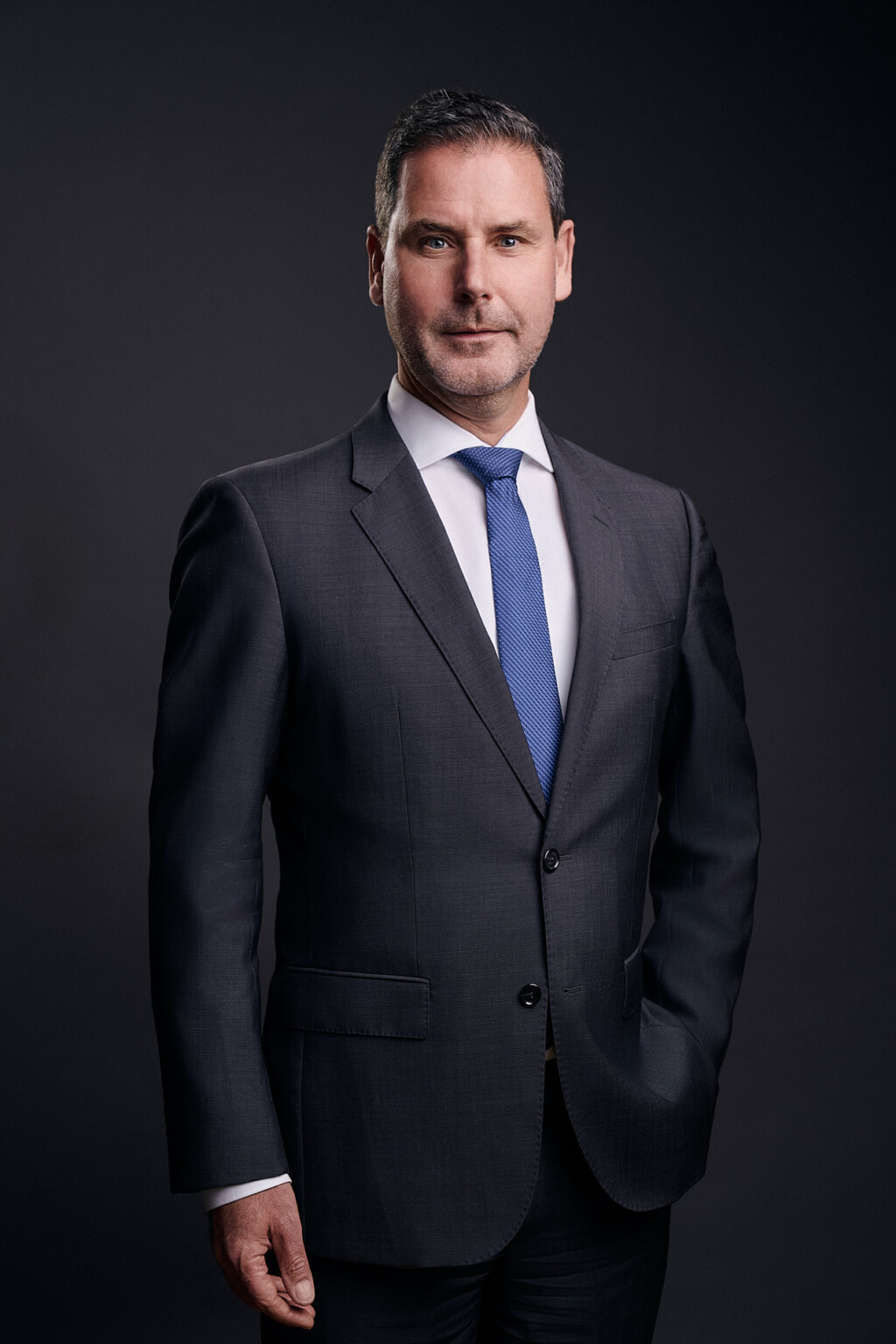 Headshot eines Mannes in dunklem Anzug mit blauer Krawatte, Businessfotograf Frankfurt