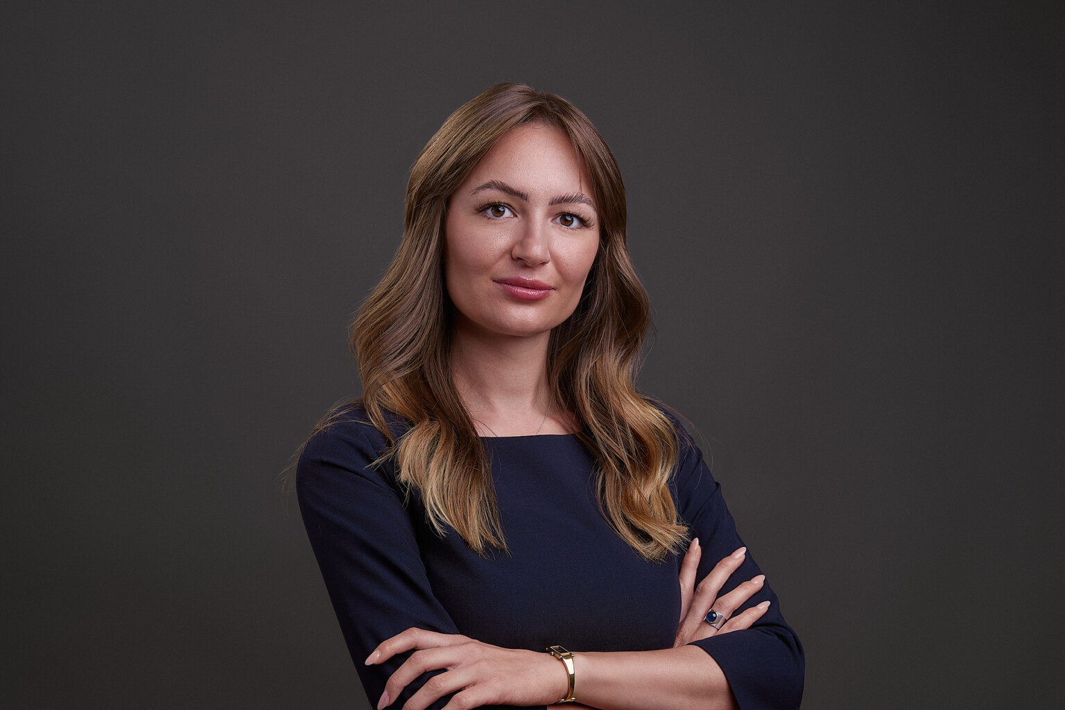 Frau mit welligem Haar und verschränkten Armen in dunkler Bluse, Business Portrait Frau Frankfurt