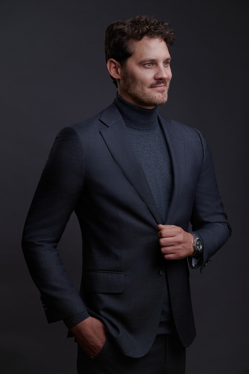Mann mit Bart in dunklem Anzug und Rollkragen, Hand in der Tasche, Business Portrait Frankfurt