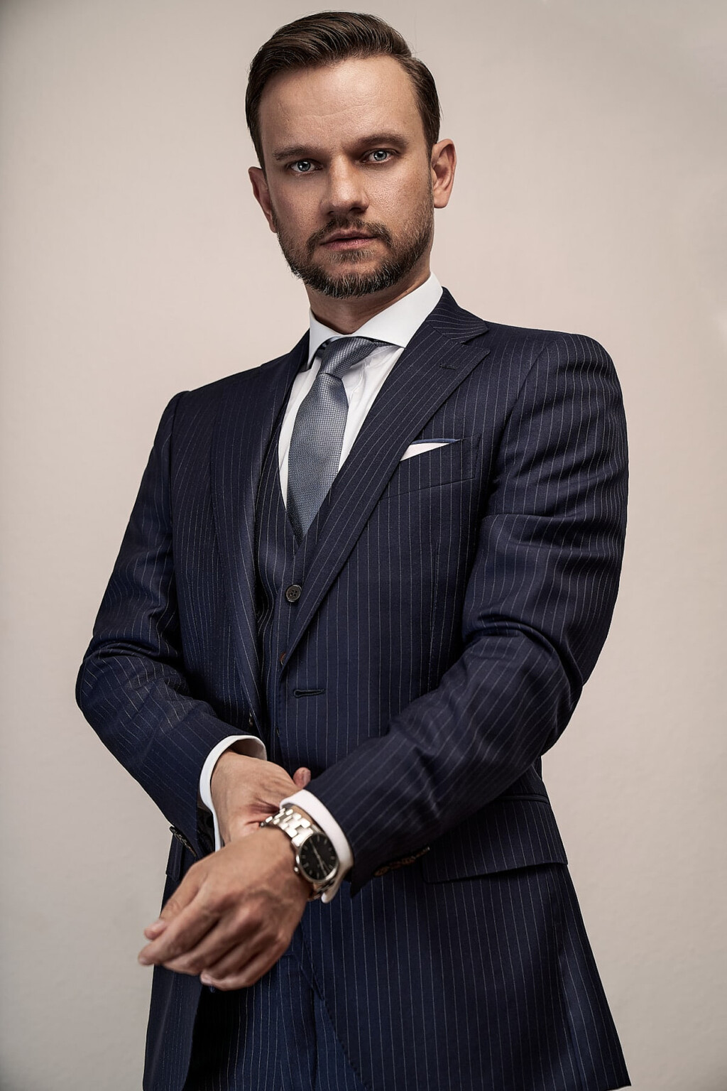 Mann im Nadelstreifenanzug mit grauer Krawatte richtet seine Uhr, Business Portrait Frankfurt
