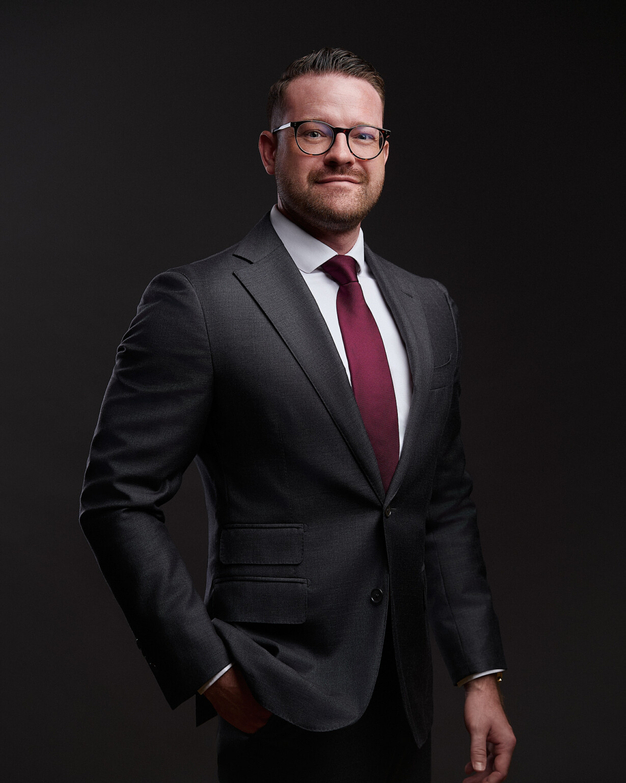 Business Portrait Mann mit Brille im dunklen Anzug mit bordeauxroter Krawatte, Fotograf Frankfurt