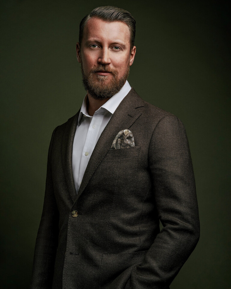 Business Portrait eines Mannes im braunen Jackett, Körper schräg zur Kamera, Hand in der Hosentasche