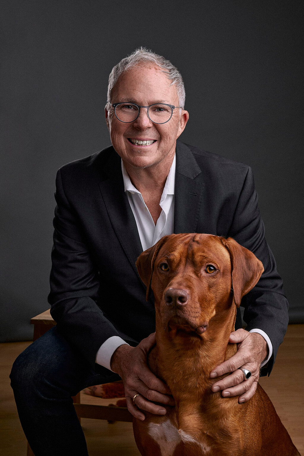 Lächelnder Mann mit Brille im schwarzen Anzug mit seinem braunen Hund, Portrait Frankfurt