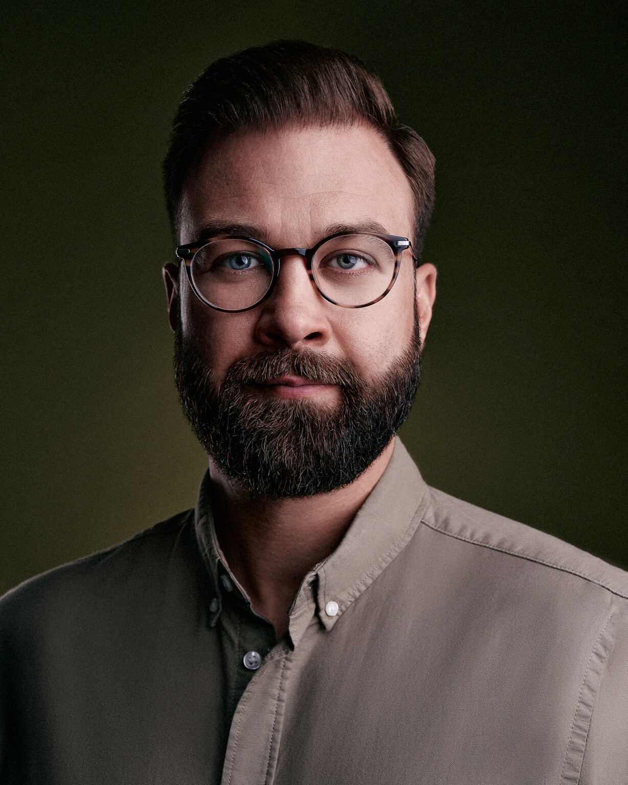Mann mit Brille und Bart im beigen Hemd vor olivgrünem Hintergrund, Corporate Portrait Frankfurt