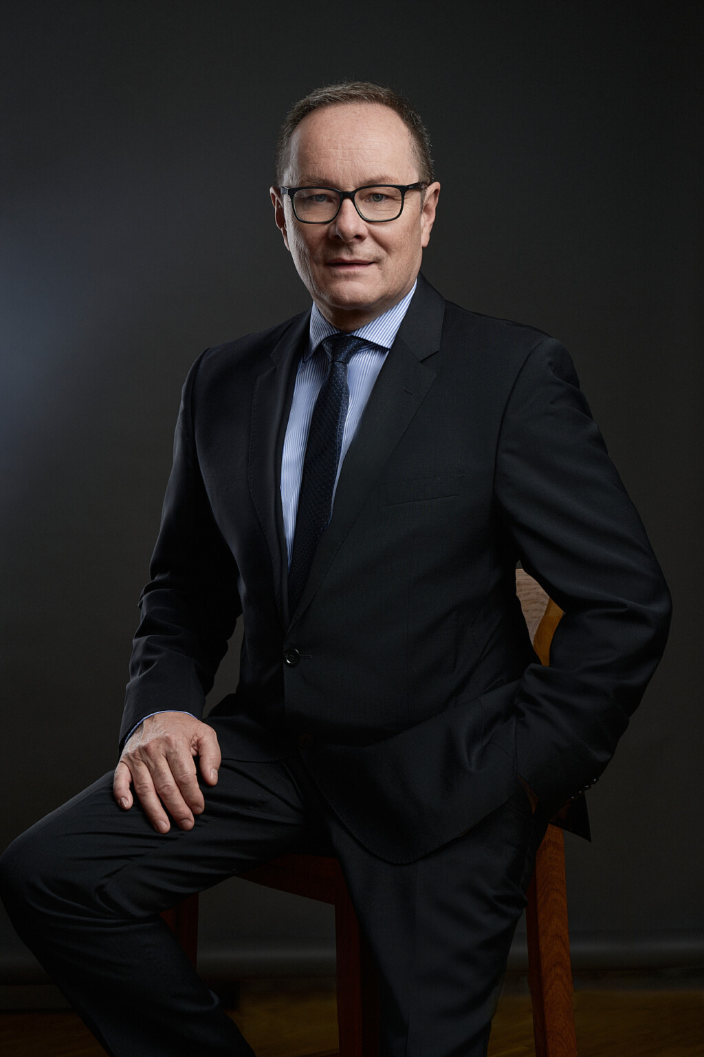 Mann in dunklem Anzug und hellblauem Hemd auf einem Holzstuhl, Business Portrait Frankfurt