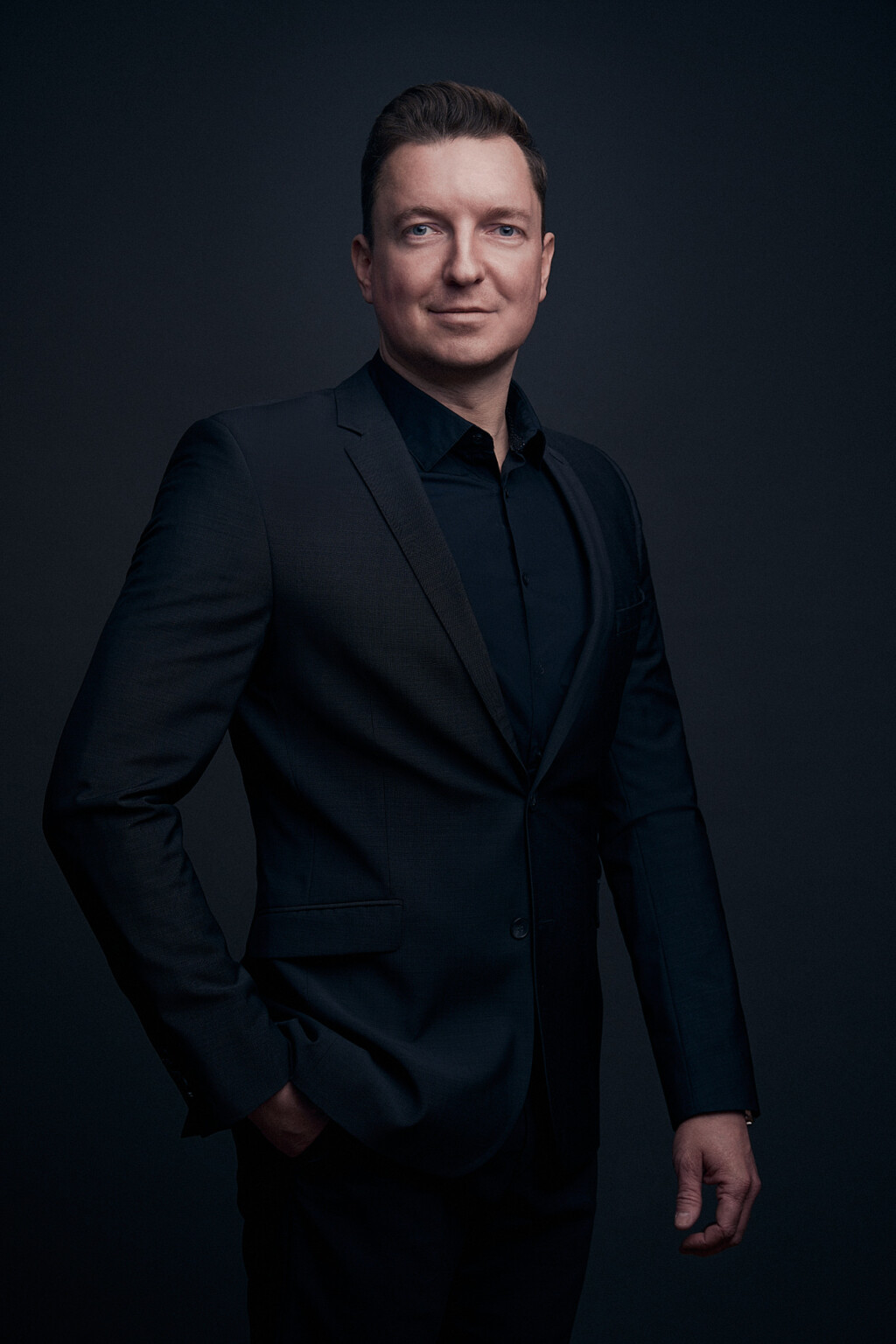 Mann in dunklem Anzug und schwarzem Hemd vor dunklem Hintergrund, Business Portrait Frankfurt
