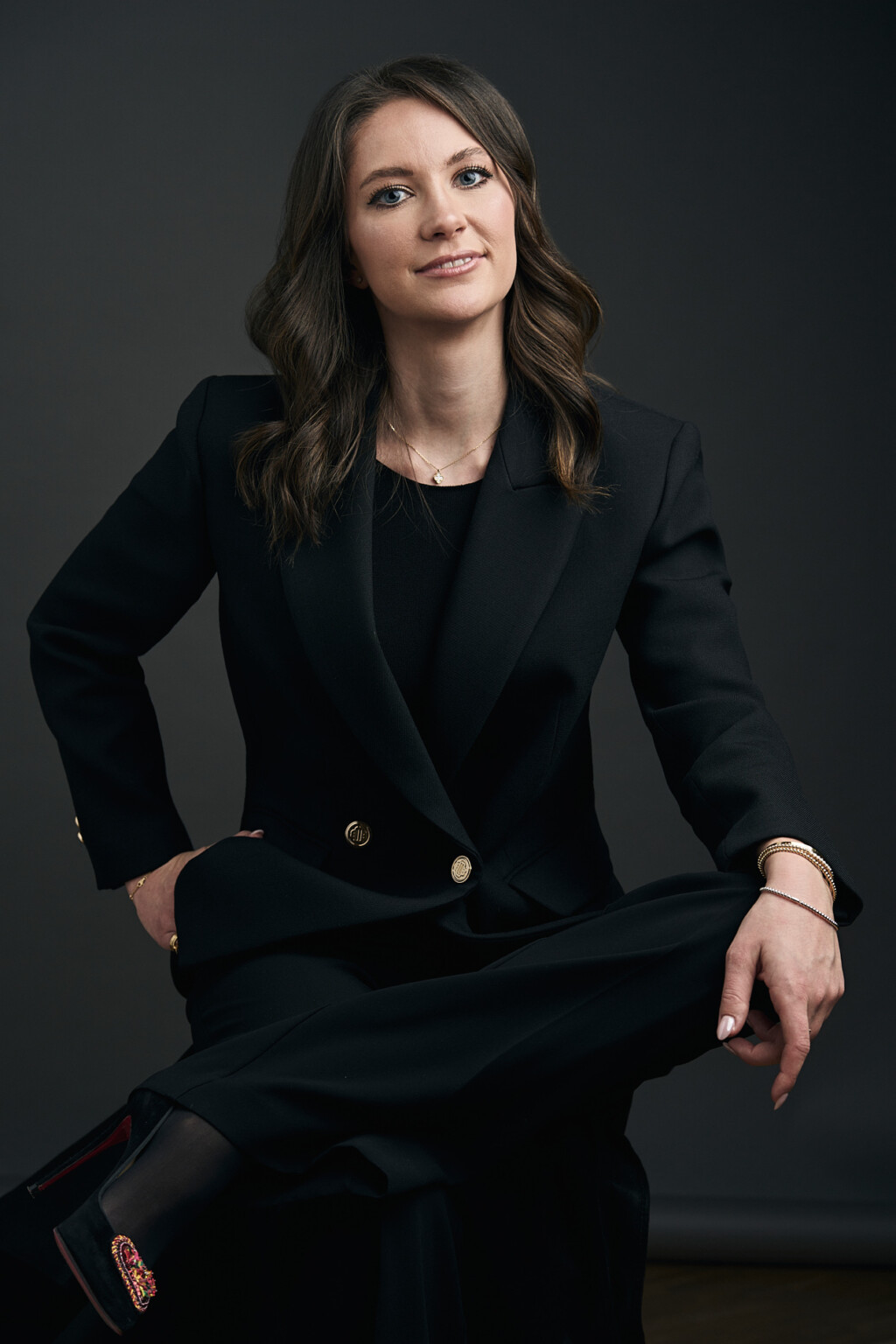 Frau im schwarzen Anzug sitzt mit übereinandergeschlagenen Beinen, Business Portrait Frau Frankfurt