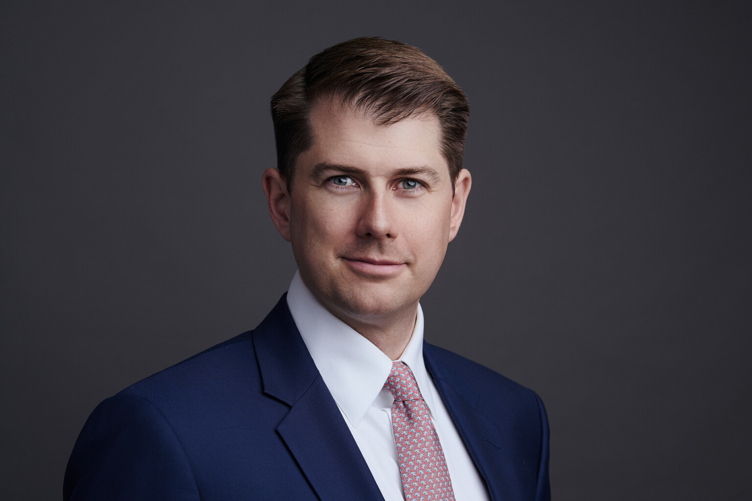 Headshot Mann in blauem Anzug mit rosa Krawatte vor dunkelgrauem Hintergrund, Fotostudio Frankfurt