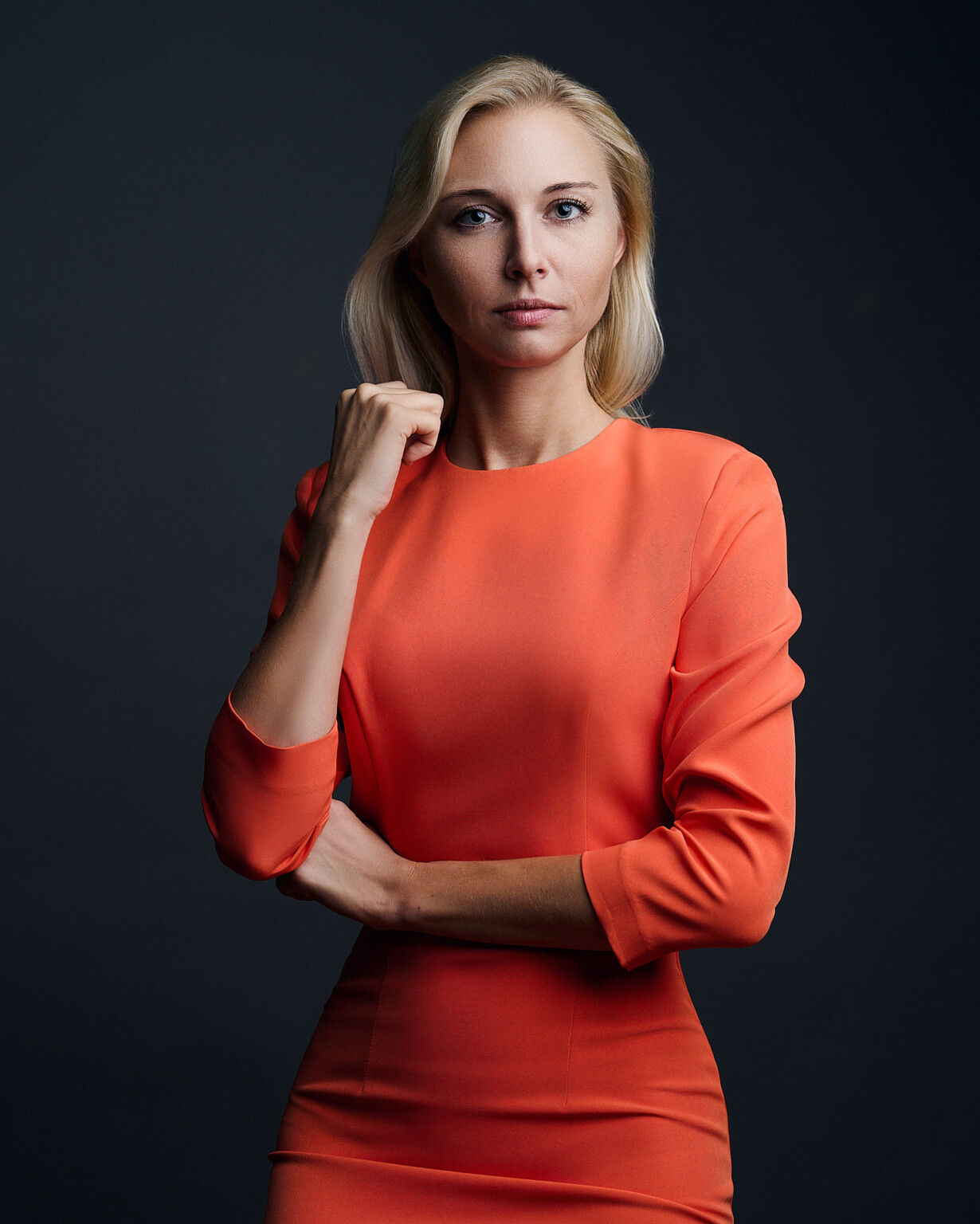 Frau mit blonden Haaren im rot-orangen Kleid vor dunklem Hintergrund, Business Portrait Frankfurt