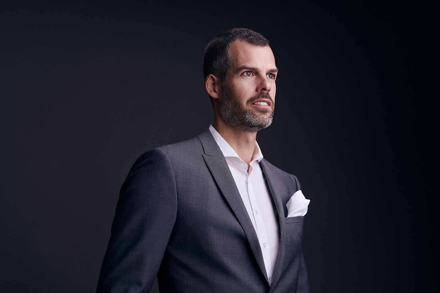 Mann im Anzug mit weißem Einstecktuch vor dunklem Hintergrund, Business Portrait Frankfurt