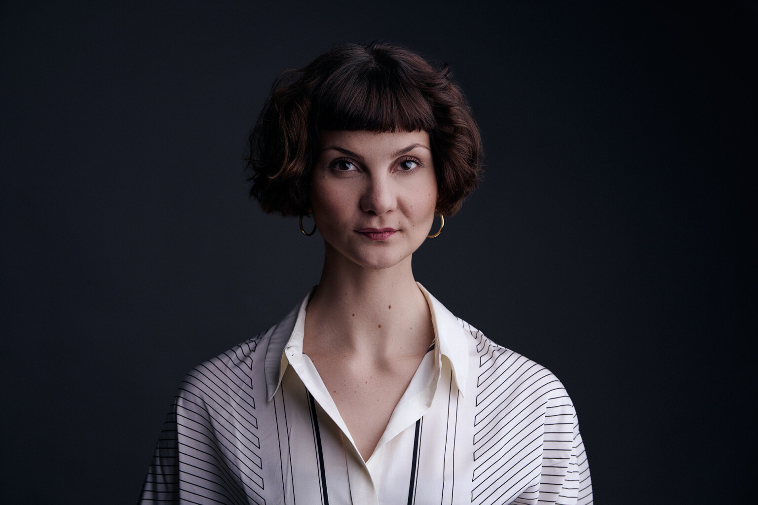 Woman with a fringe in a striped blouse against a dark background, business portrait of a woman, Frankfurt
