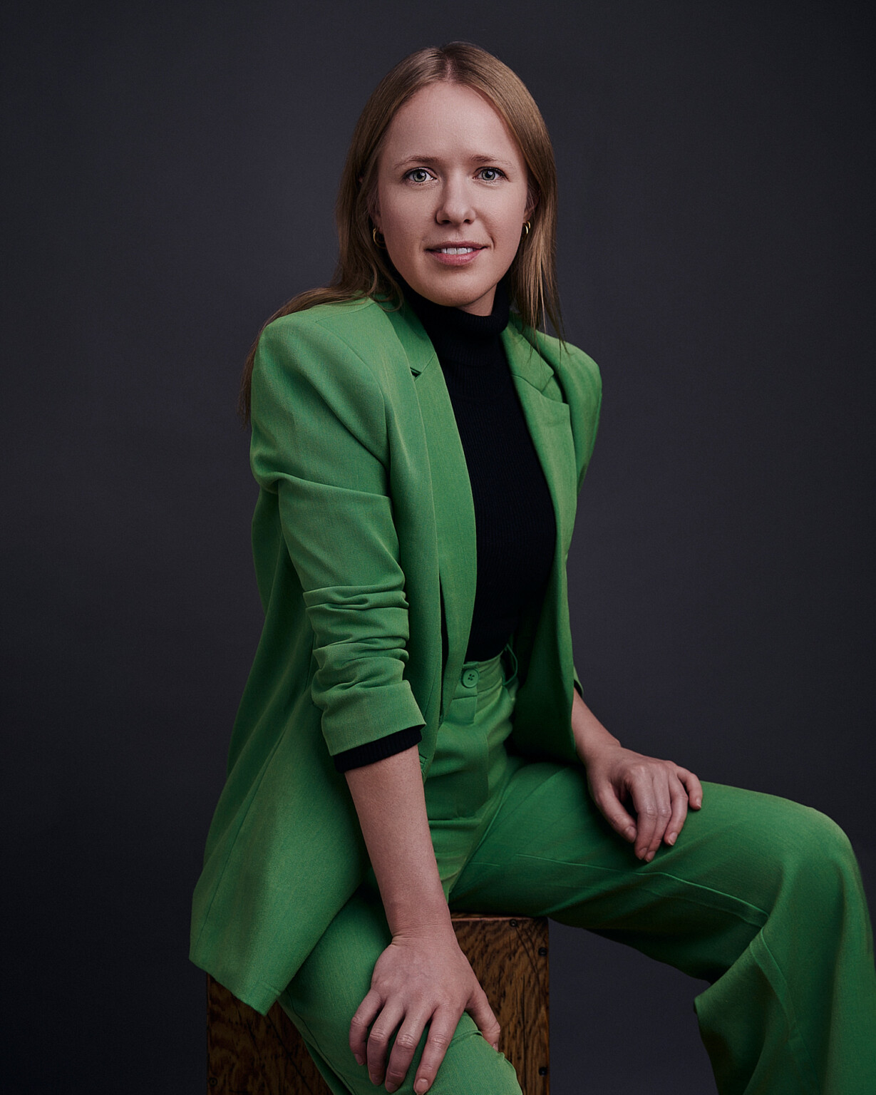 Frau mit blonden Haaren im grünen Anzug auf einem Holzhocker, Business Portrait Frau Frankfurt