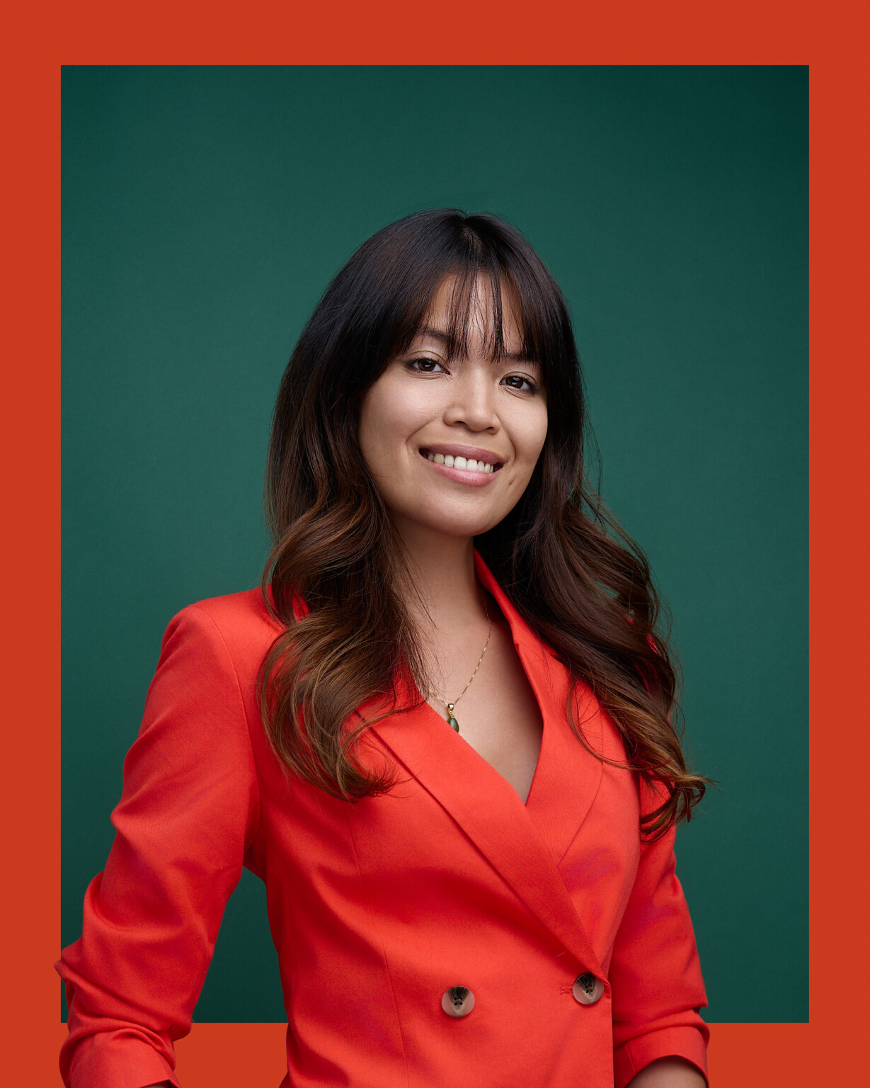 Business Headshots 16 Smiling woman in an orange blazer against a green background, business portrait of a woman, Frankfurt