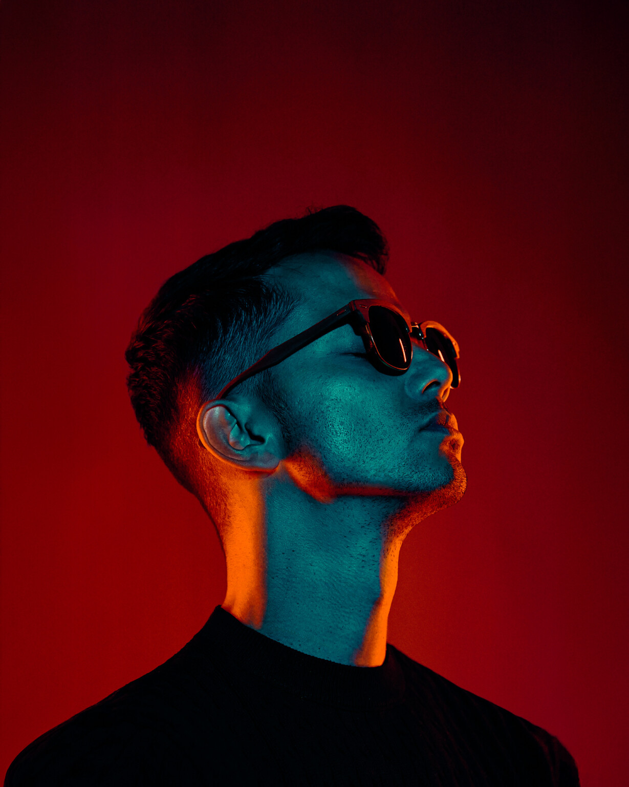 Mann mit Sonnenbrille vor rotem Hintergrund mit blauem und orangem Licht, Casual Portrait Frankfurt