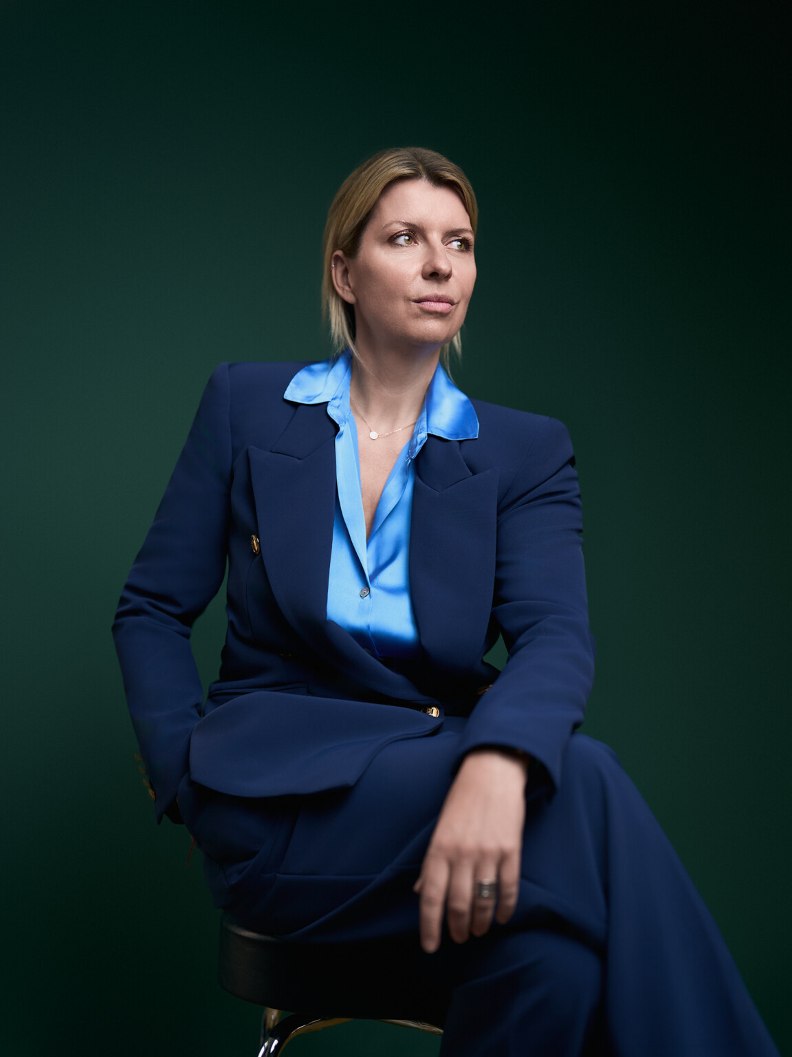 Geschäftsfrau im dunkelblauen Anzug mit blauer Bluse auf einem Hocker, Corporate Portrait Frankfurt