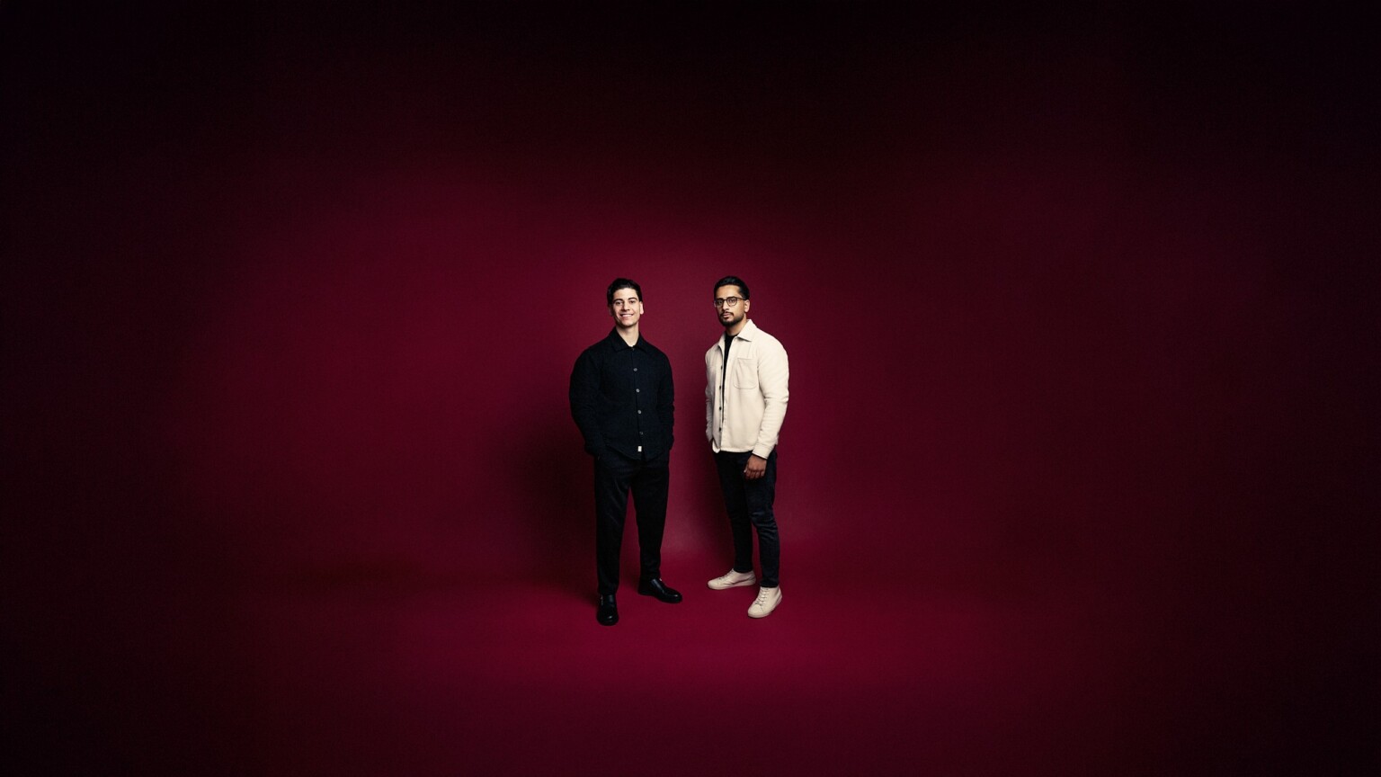 Two men in business casual clothing against a dark red background, business casual portrait Frankfurt