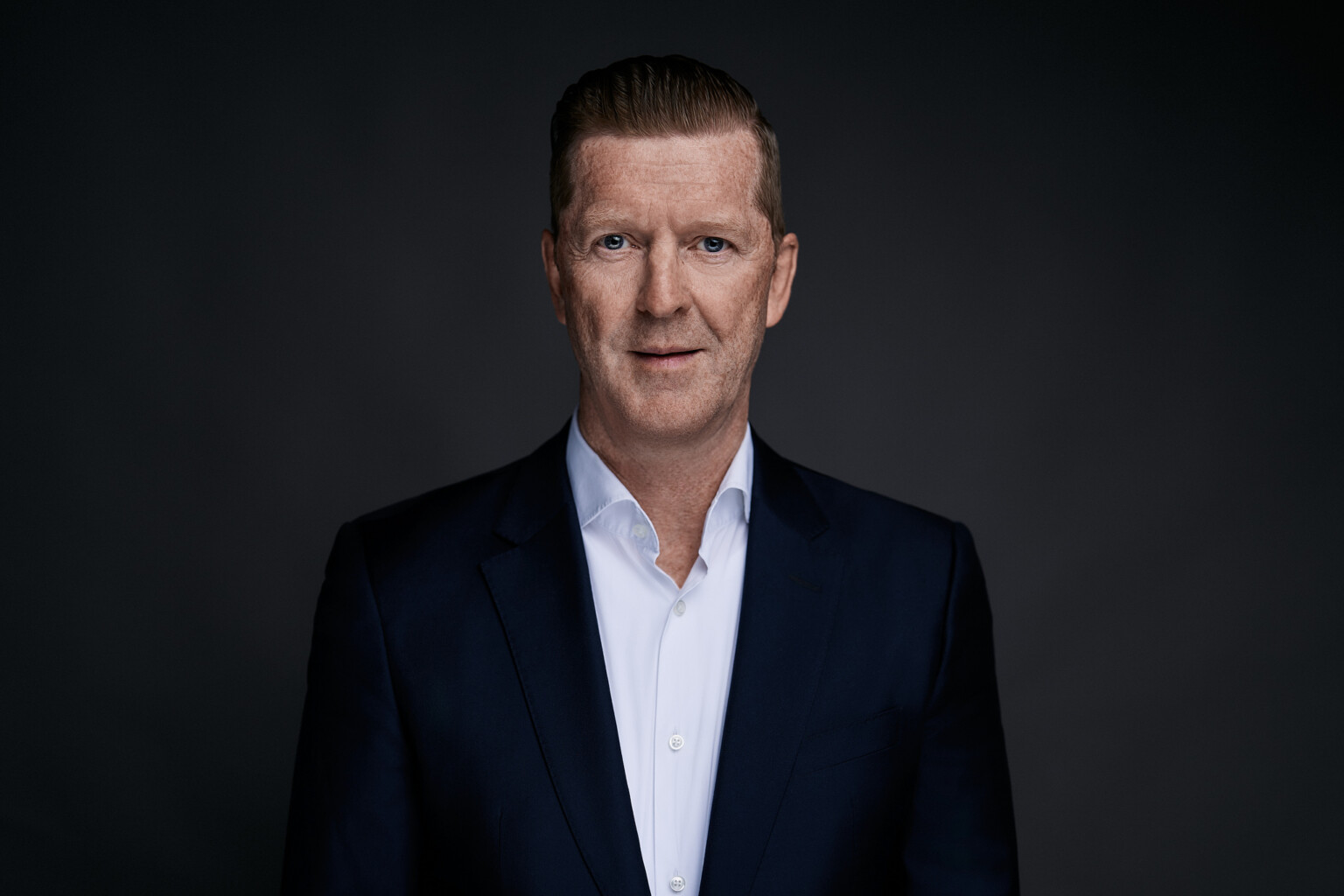 Thomas Dries im Business Portrait: frontal, dunkelblaues Sakko, weißes Hemd, dunkler Studiohintergrund in Frankfurt