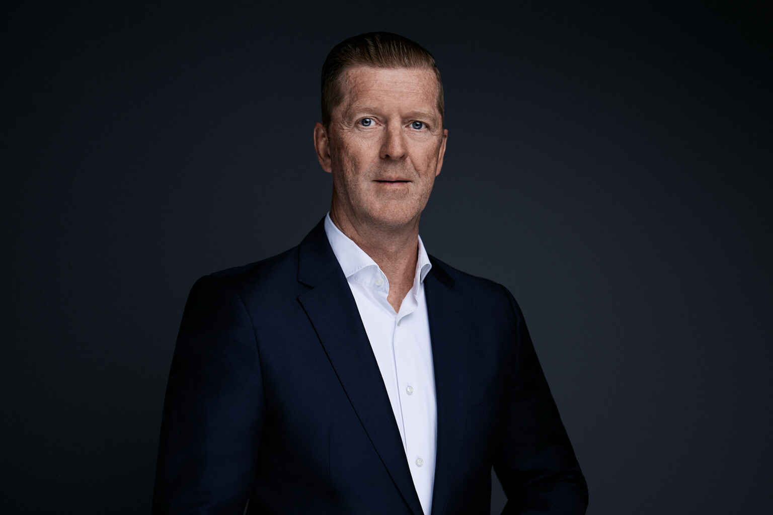 Board portrait of Thomas Dries: three-quarter profile, navy suit, open white shirt, Arthouse Studio Frankfurt