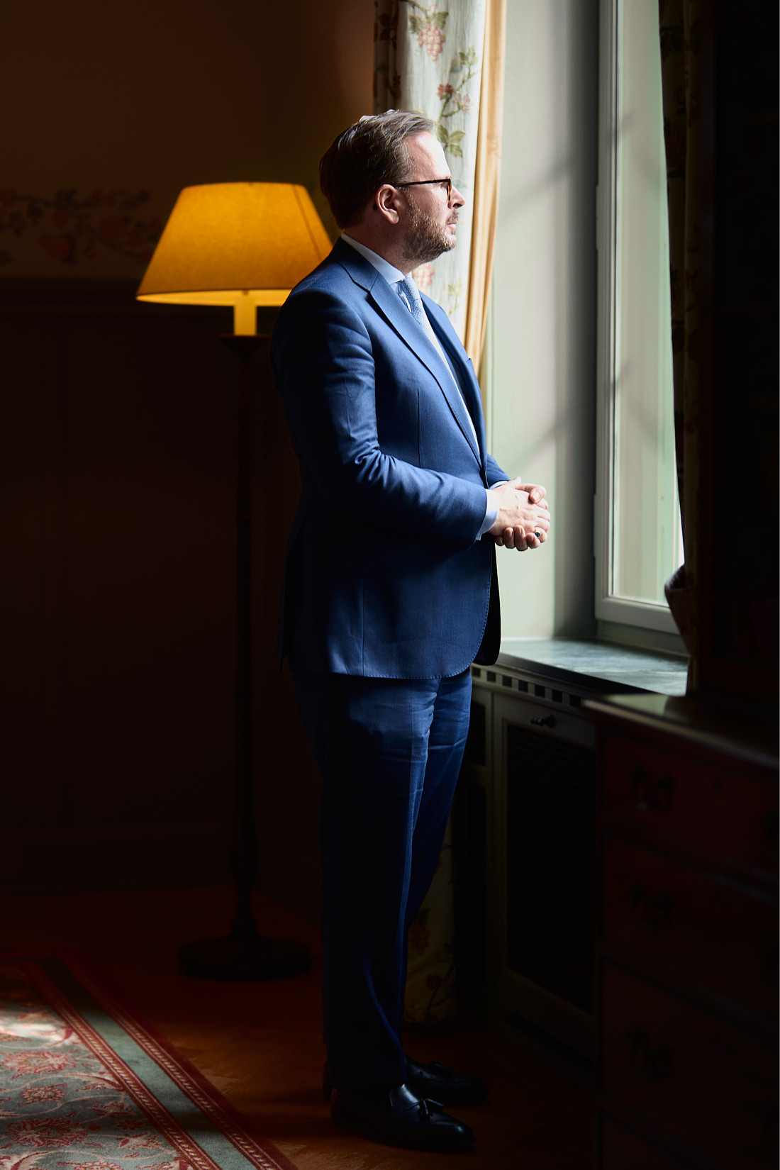 Executive Portrait eines Mannes im blauen Anzug am Fenster eines Altbau-Büros, Business Portrait vor Ort